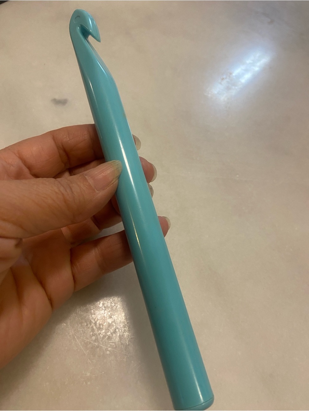 Vintage Hand holding a large plastic crochet hook